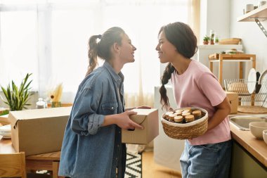 İki kadın sıcak ve davetkar mutfaklarında kutuları açarken şefkatle sarılıyorlar..