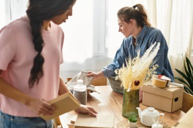 İki kadın eşyalar sıralanırken ve birbirlerine eşlik ederken sıcak bir atmosfer yaratırlar..