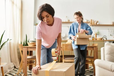 İki kadın kutuları açıp sıcak bir alan yaratırken evlerinde hassas bir anı paylaşıyorlar..