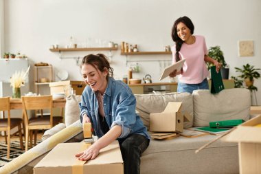 Kutuları açarken iki kadın kahkahalarını paylaşıyor ve sevgi dolu sıcak bir alan yaratıyorlar..