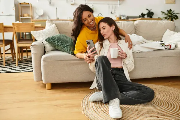 İki kadın, rahat bir kanepede oturup birlikte eğlenirken gülüşür ve güler..