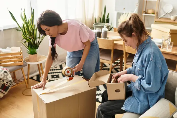 İki kadın neşeli bir şekilde, bitkiler ve sıcaklıkla çevrili parlak oturma odalarında kutuları açıyor..