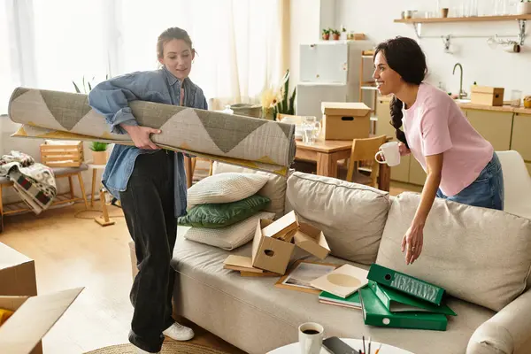 İki kadın neşe içinde yeni yaşam alanlarını kutular ve kişisel dokunuşlarla dolduruyorlar..