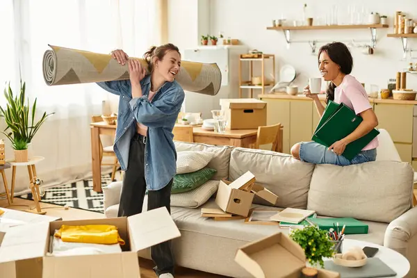 İki kadın sevinçle yeni yerlerini düzenliyor, kutular ve dekorlar arasında gülücükler ve kahkahalar paylaşıyorlar..