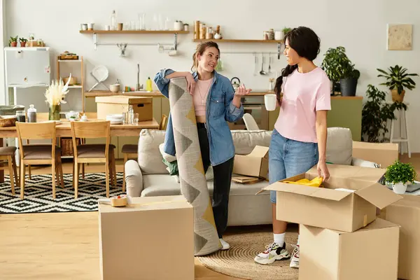 İki kadın, eşyalarını sıcak, davetkar bir yere yerleştirirken keyifli bir anı paylaşıyor..