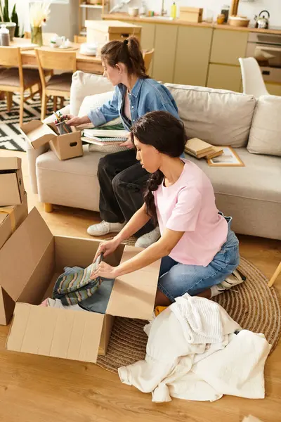 İki kadın evlerinde kutuları açarken ve mekanlarını düzenlerken keyifli anları paylaşıyorlar..