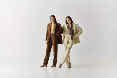 Şık ikiz kardeşler, şık kıyafetlerini ve kız kardeş bağlarını sergileyerek özgüvenle ayakta duruyorlar..