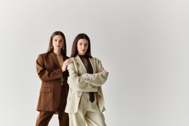 İki güzel genç ikiz kız kardeş güven içinde poz veriyor, şık kıyafetlerini ve güçlü bağlarını sergiliyorlar..