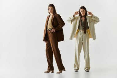 Güzel ikiz kardeşler şık kıyafetler giyip şık bir stüdyoda poz veriyorlar..