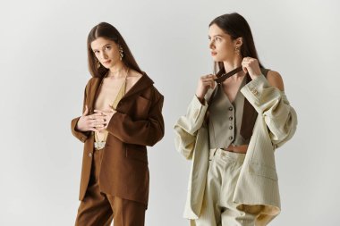 İki güzel genç kız kardeş şık bir stüdyoda zarif bir poz vererek, bir bağ kurma anını paylaşıyorlar..