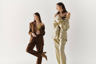 İki genç ikiz kız kardeş birlikte şakacı poz verirken eşsiz moda tarzlarını sergilerler..