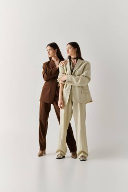 İkiz kardeşler şık, uyumlu takım elbiseler içinde zerafet ve birlik içinde, modayı kutluyorlar..