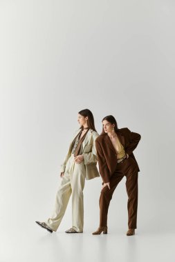 İkiz kardeşler, şık bir ortamda neşeli bir şekilde poz verirken bireysel tarzlarını ifade ederler..