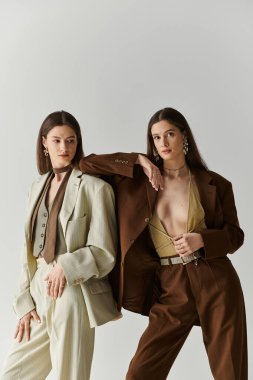 Güzel ikiz kız kardeşler şık kıyafetler, ışık saçan stil ve entelektüellik içinde rahatça poz verirler..