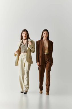 Şık giyinmiş ikiz kardeşler parlak bir stüdyoda güvenle yürürler..