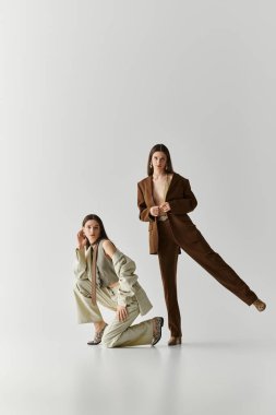 İkiz kardeşler şık kıyafetler içinde zarifçe poz verirken cazibe ve tarz sergilerler..