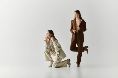 İki güzel ikiz kardeş zarif kıyafetler giyip çağdaş tarzda uyum içinde poz veriyorlar..