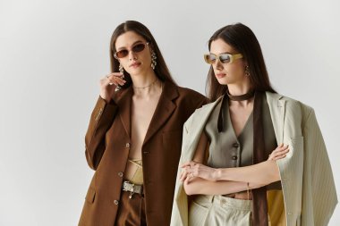 İkiz kardeşler şık kıyafetler içinde dururlar, bağlarını ve paylaşılan tarzlarını vurgularlar..