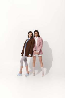 İki güzel ikiz kardeş birbirlerine yakın durarak benzersiz tarzlarını sergiliyorlar..