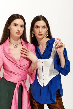 Moda ikizleri modern bir stüdyoda şık kıyafetlerini sergilerken birbirlerine bağlanırlar..