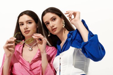 İkiz kardeşler şık kıyafetler ve aksesuarlarla rahatça poz verirler..