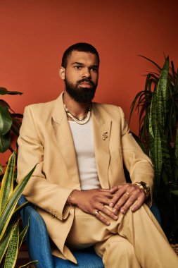 Yakışıklı bir adam mavi bir sandalyeye rahatça oturur ve yanında canlı bitkilerle yaz zarafetini kucaklar..