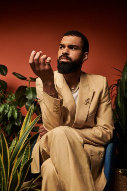 Genç adam yaz kıyafetleri giyerken kendine güvenir. Sıcak, renkli bir arka plana karşı..