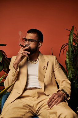 Yakışıklı adam şık bir ortamda, gösterişli bir yaz modasında ve kendine güvenen bir tavırda rahatlıyor..