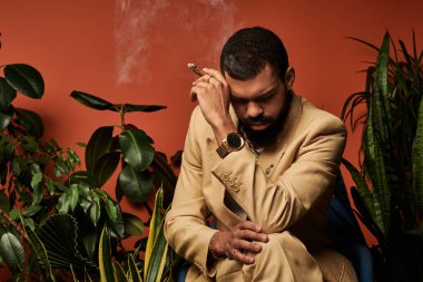 Hafif giysili şık bir genç adam yeşilliklerle çevrili sessiz bir anın tadını çıkarıyor..