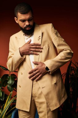 Havalı bir yaz elbisesi içinde, yakışıklı bir adam hareketli bir arka plana karşı duruş sergiliyor..