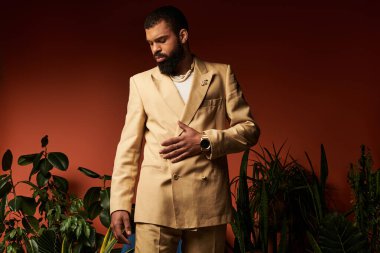 Yakışıklı bir adam, bitkilerle çevrili canlı bir ortamda şık yaz kıyafetleri sergiliyor..