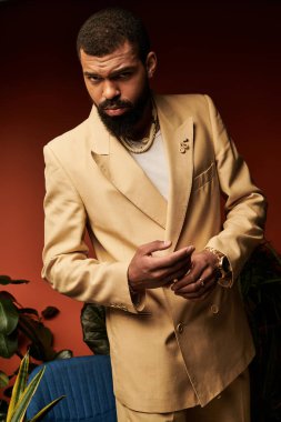 Açık renk takım elbiseli genç bir adam renkli iç mekan bitkilerinin arasında şık bir görünüm sunar..