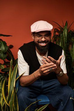 Neşeli genç adam hayat dolu bir ortamda gevşiyor, bitkilerle çevrili, yaz tarzını kucaklıyor..