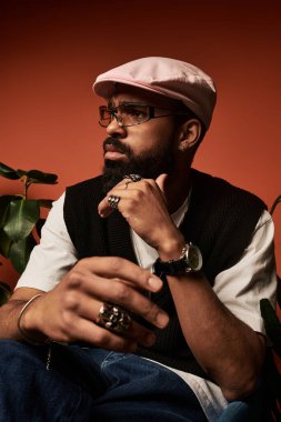 Yakışıklı genç adam yaz modasını sergiliyor, aksesuarlı ve düşünceli ortamda.