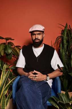 Yakışıklı adam, canlı bitkilerle çevrili şık bir sandalyede gevşiyor ve yaz estetiğini kucaklıyor..