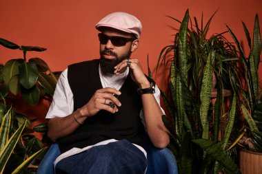 Genç adam bir yaz öğleden sonrasının keyfini çıkarıyor, modaya uygun aksesuarları ve sakin tavırları var..