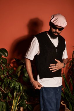 Genç bir adam, bitkilerle çevrili sıcak ve dokulu bir arka plana karşı modaya uygun bir yaz elbisesi modelliyor..