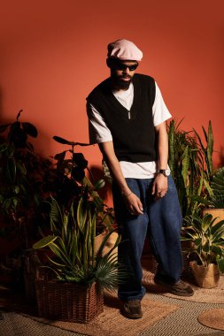 Şık bir genç adam yaz modasında canlı bitkiler arasında rahatça poz verir..