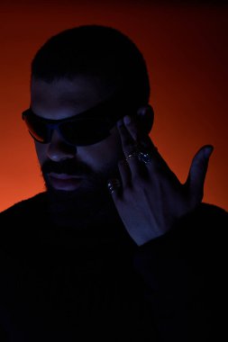 Yakışıklı genç adam, güneş gözlükleriyle kendine güvenerek poz veriyor. Cesur aksesuarlarıyla yaz modasını sergiliyor..