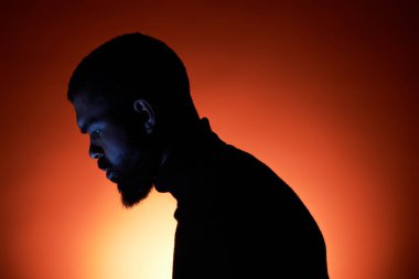 Şık bir genç adam, canlı bir günbatımı geçmişine rağmen yaz akşamının tadını çıkarıyor.