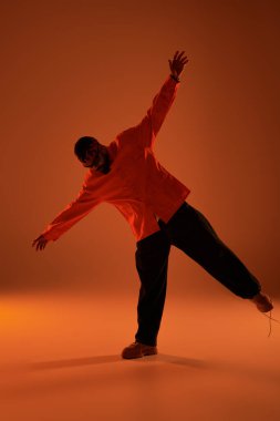 Genç bir adam sıcak ve canlı bir ortamda kendine güvenen bir pozla yaz estetiğini ifade eder..