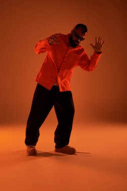 Genç adam renkli kıyafetler ve enerjik ifadeyle yaz modasını sergiliyor, neşe saçıyor..