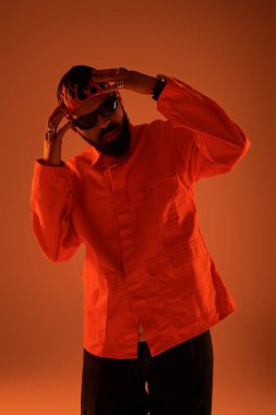 Genç bir adam cesur turuncu bir elbise içinde, yaz havasını yakalıyor..