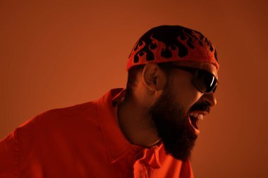 Turuncu elbiseli şık bir adam, canlı enerji ve tavırlarıyla yaz havasını yansıtır..