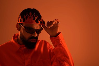 Yakışıklı adam yaz stili vurucu hareketler sergiliyor, sıcak ışık atmosferine güveni yansıtıyor.