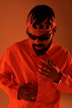 Genç bir adam yaz modasına güveniyor, renkler ve kalın aksesuarlar sergiliyor..