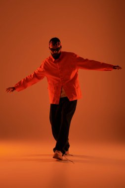 Parlak turuncu giyinmiş yakışıklı adam sıcak tonlarla aydınlatılmış neşeli bir anın tadını çıkarıyor..