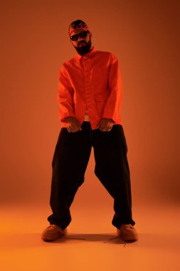 Şık bir genç adam dikkat çekici turuncu bir elbiseyle, yaz havasını somutlaştırıyor..