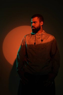 Genç bir adam kendinden emin bir şekilde sanatsal ışıklandırma, gösterişli yaz atmosferi ve modern moda ile ayakta duruyor..