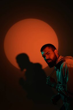 Genç bir adam, ufukta parlayan bir güneşin yanında poz verirken yaz tarzını sergiliyor..